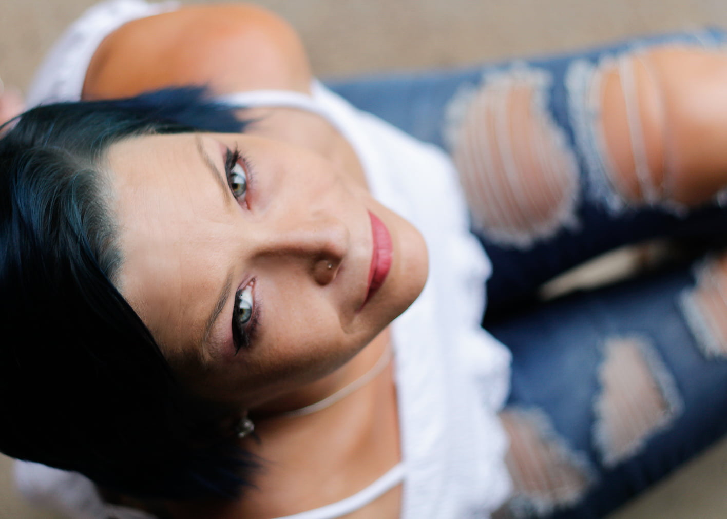 Woman with blue hair looking up with ripped jeans and white shirt