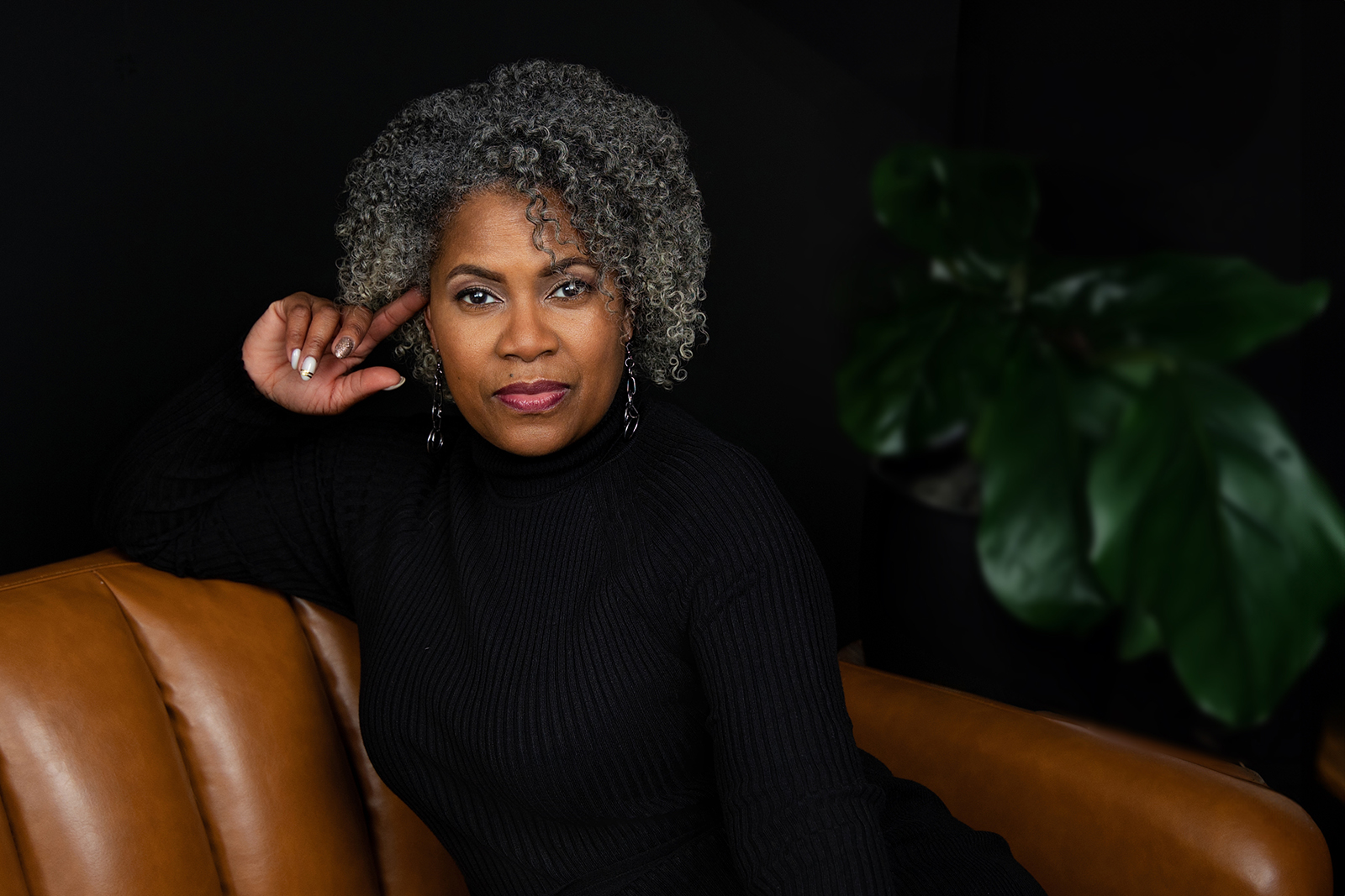 Black woman in black knit top and curly black and white hair