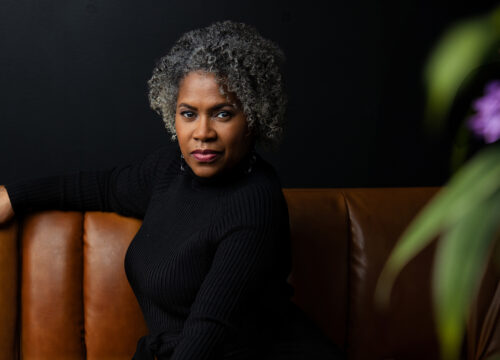 Black woman in black knit top and curly black and white hair