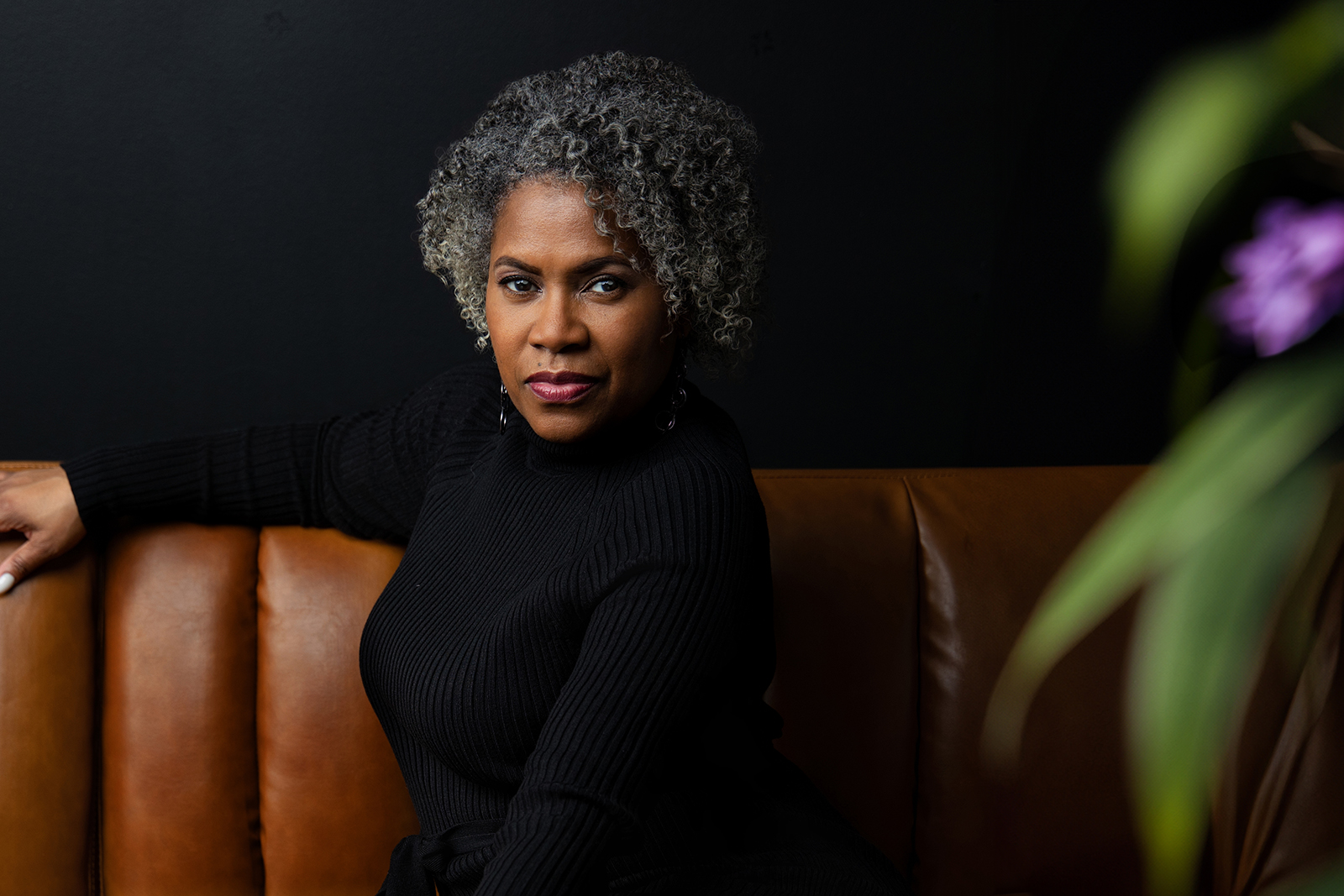 Black woman in black knit top and curly black and white hair